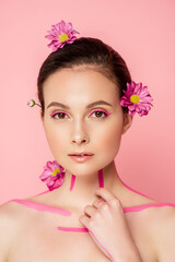 Fototapeta na wymiar naked beautiful woman with pink lines on body and flowers in hair isolated on pink