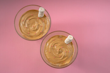 Top view of two glasses of popular Korean Dalgona coffee on pink background. Made at home