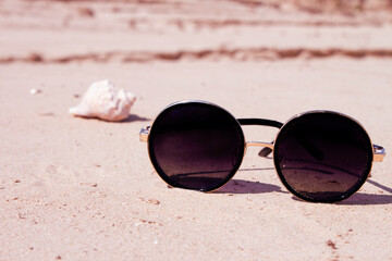 Sunglasses on the sand. Close up. The concept of rest, vacation. Summer time, travel, beach, sea, sun, sunbathing. Copy space.