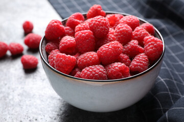 Delicious fresh ripe raspberries in bowl on grey table, closeup