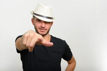 Studio shot of handsome bearded Hispanic man wearing hat