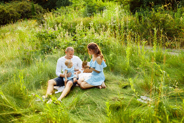 Fototapeta premium Smiling mother and father with little baby girl enjoy picnic in summer