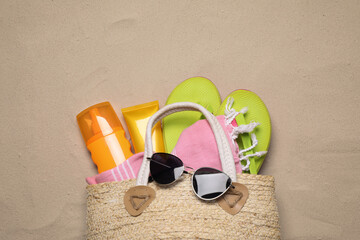 Fototapeta na wymiar Bag with beach accessories on sand, top view