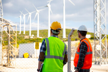 Young engineers looking and checking wind turbines at field