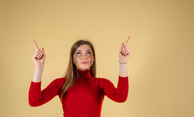 Young elegant woman pointing to the top with fingers at yellow background