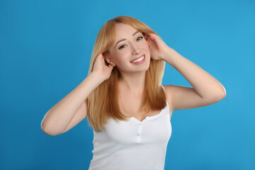 Beautiful young woman with blonde hair on blue background