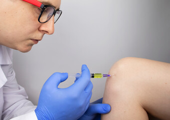 An orthopedic surgeon gives an injection in the knee. Treatment of osteoarthritis with hormonal...