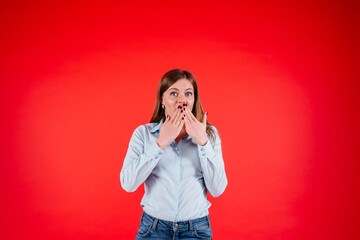 Surprised young woman holds her hands near the mouth, wondering in excitement