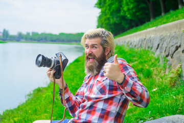 Bearded man taking photographs. Hobby and travel. Young man taking photo with his camera on street. Enjoying free time. Attractive man using professional camera. Handsome man with digital camera.