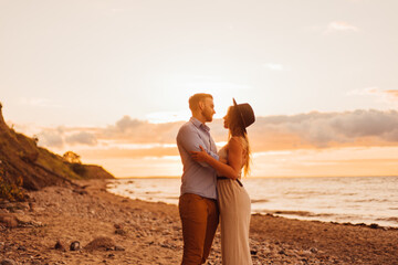 Young couple hugging in sunset on the beach