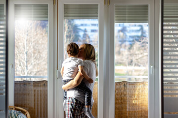 Young single mother hugging and playing with her little son at home.Happy family,mother and son toddler laughing and hugging on the balcony at home.Shot of adorable boy affectionately kissing mother.