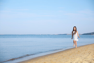 Cute little child running at sandy beach on sunny day
