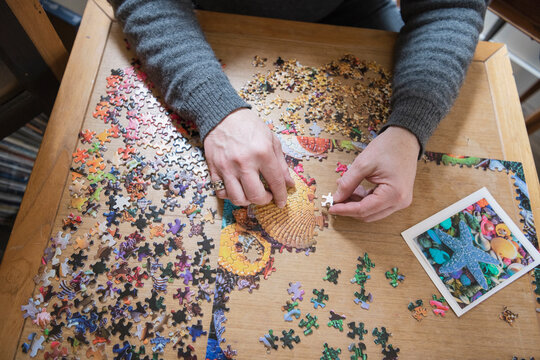 Man Assembling Jigsaw Puzzle On Table