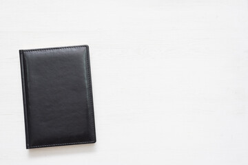 Black leather book on the white table background.