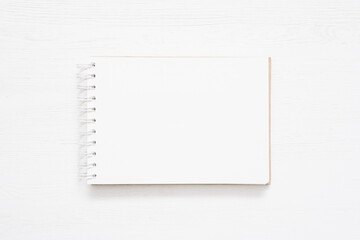 Notepad with blank pages on the white wooden table background.