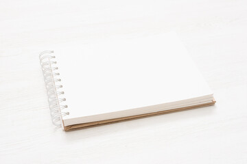 Notepad with blank pages on the white wooden table background.