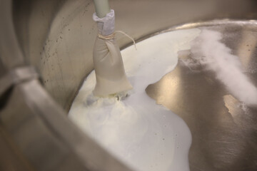 Pouring milk into curd preparation tank at cheese factory, closeup