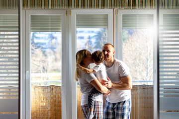 Happy family having fun together.Married couple enjoy having fun time with cute little son at home.Family weekend with child.Shot of young father kissing and cuddle his wife and their sweet little son