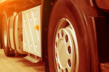 Front wheel with disc cap of semi-truck trailer european type close-up. Warm editing with pop filtered sunshine.