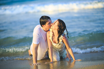 newlywed in wet clothes flirting lying on beach.