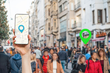 A hand holds a smartphone with an online maps app. In the background, people walking down the street, in a blur. Concept of online maps and travel