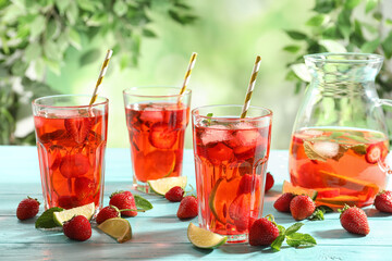 Refreshing drink with strawberry and lime on light blue wooden table