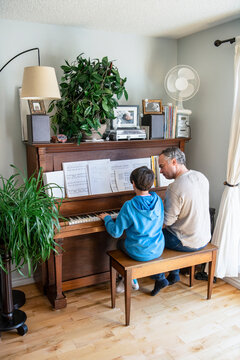 Father and son playing piano at home