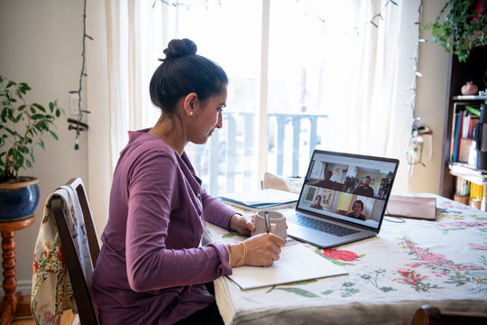 Woman with laptop video conferencing with colleagues from home