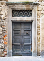 Old brown wood door. Weathered old wooden texture. Old brick wall. Old building in Bergamo, Italy. Grunge vintage authentic background.