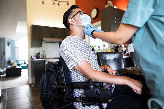 Healthcare worker helping quadriplegic man with face mask