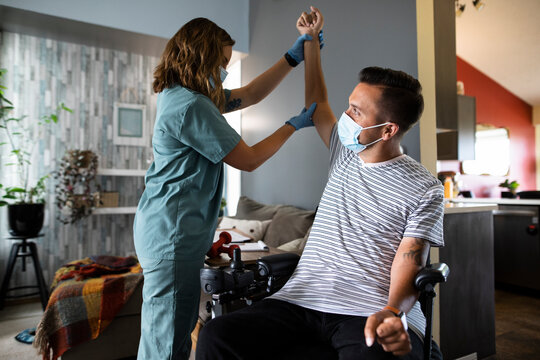 Healthcare worker helping quadriplegic man exercise arm
