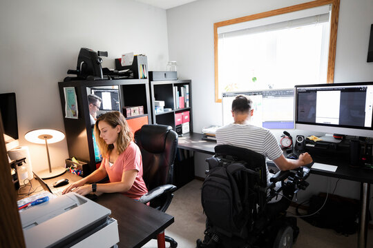 Quadriplegic man and girlfriend working together in home office