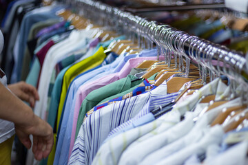 men shirts hang on hangers in a clothing store. Buying and selling, summer discounts.
