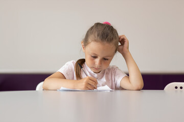 Young girl taking notes in class at school bending over his paperwork