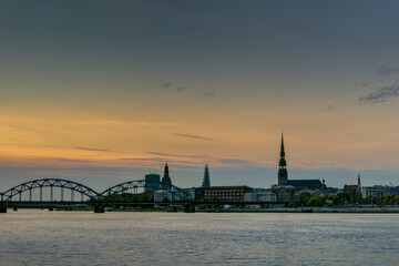 Fototapeta premium Night view on the illuminated riverside with reflection on the river in Riga,