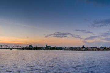 Fototapeta premium Night view on the illuminated riverside with reflection on the river in Riga,