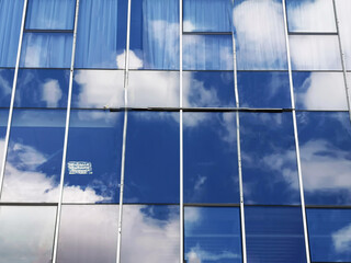 Blue sky and clouds are reflected in the windows of a glass building