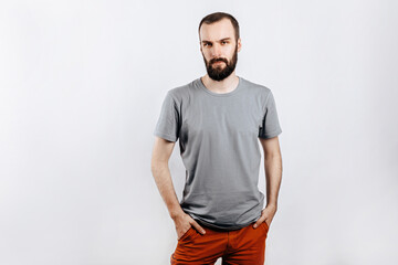 A handsome brutal brunette man with a beard in a gray shirt looks seriously at the camera, holds...