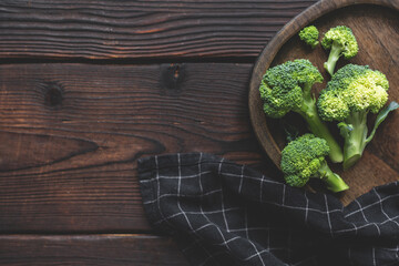 Fresh green organic broccoli vegetable on a woofen cutting board on a dark rustic wooden...