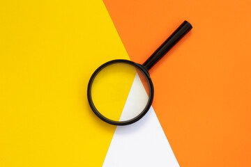 Magnifying glass against colorful background flat lay minimal creative concept.