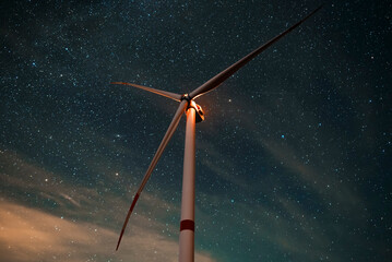 Wind turbine in the night at the stars background. Environment and renewable energy
