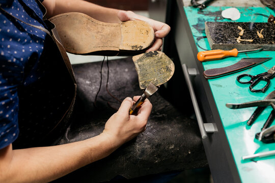 Male shoemaker using pliers to remove shoe sole. Cobbler at work.