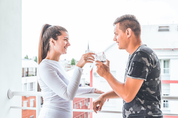 A girl and a boy in love toast with a drink on the terrace