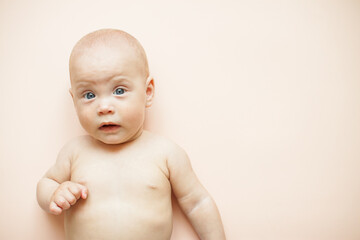 Little cute baby lies on a light pink background. Free space for text.