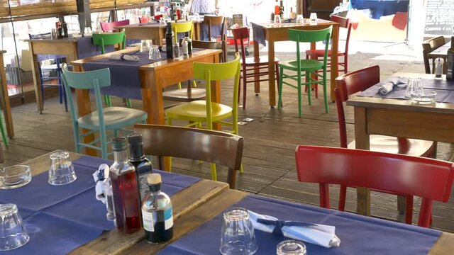 Typical Italian trattoria, with wooden tables and multicolored chairs. 