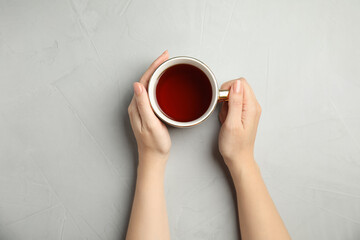 Woman with cup of tea at light table, top view
