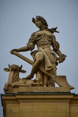 A fragment of the roof of a building with a sculpture of a woman with a cow