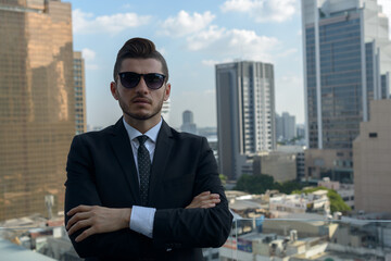 Handsome bearded Hispanic businessman against view of the city