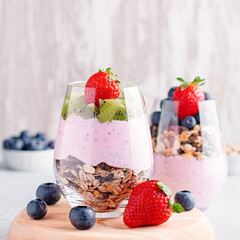 Superfoods layered pudding with granola, blueberry and strawberry in glasses. Yogurt with chia seeds, berries, kiwi and muesli for healthy breakfast, copy space. Perfect for summer snack or dessert