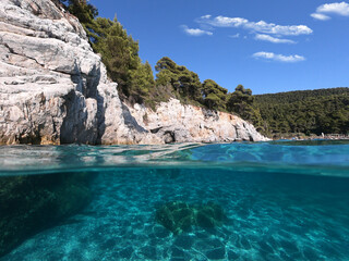 Underwater and sea level photo of amazing tropical rocky turquoise clear seascape with caves and natural pine trees